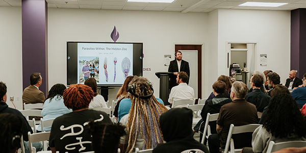 Students in a classroom looking at the board that reads, "Parasites Within: The Hidden Zoo."
